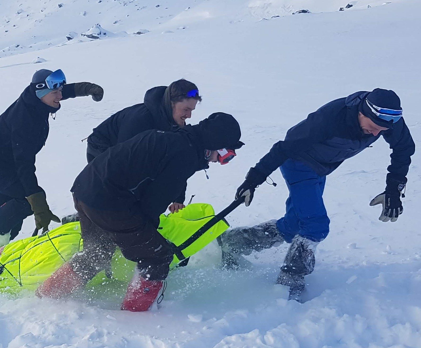 Rescue personnel moving a casualty through snow in a Thermosaver during training